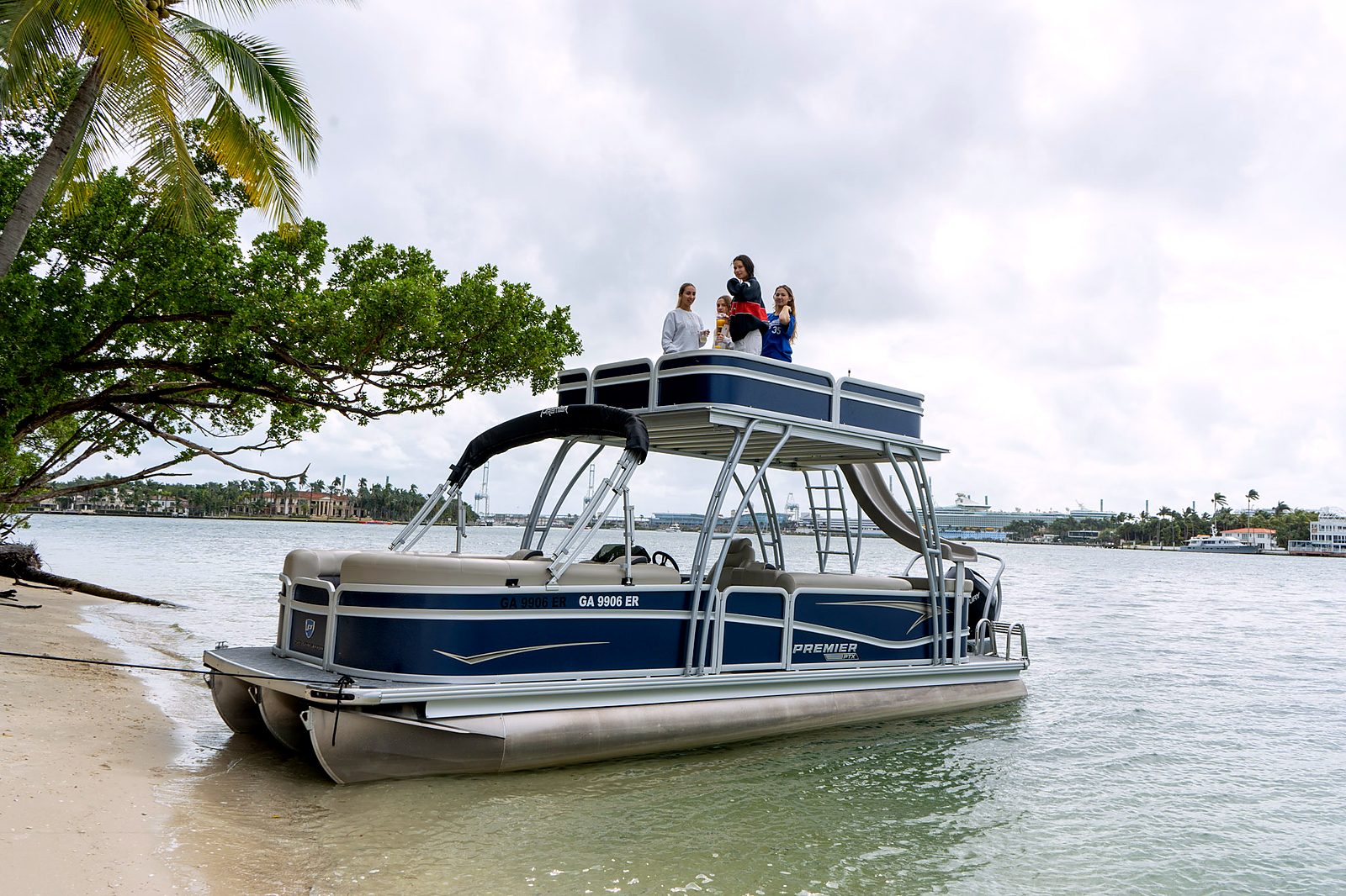 Double-deck tritoon at a beach with palm trees