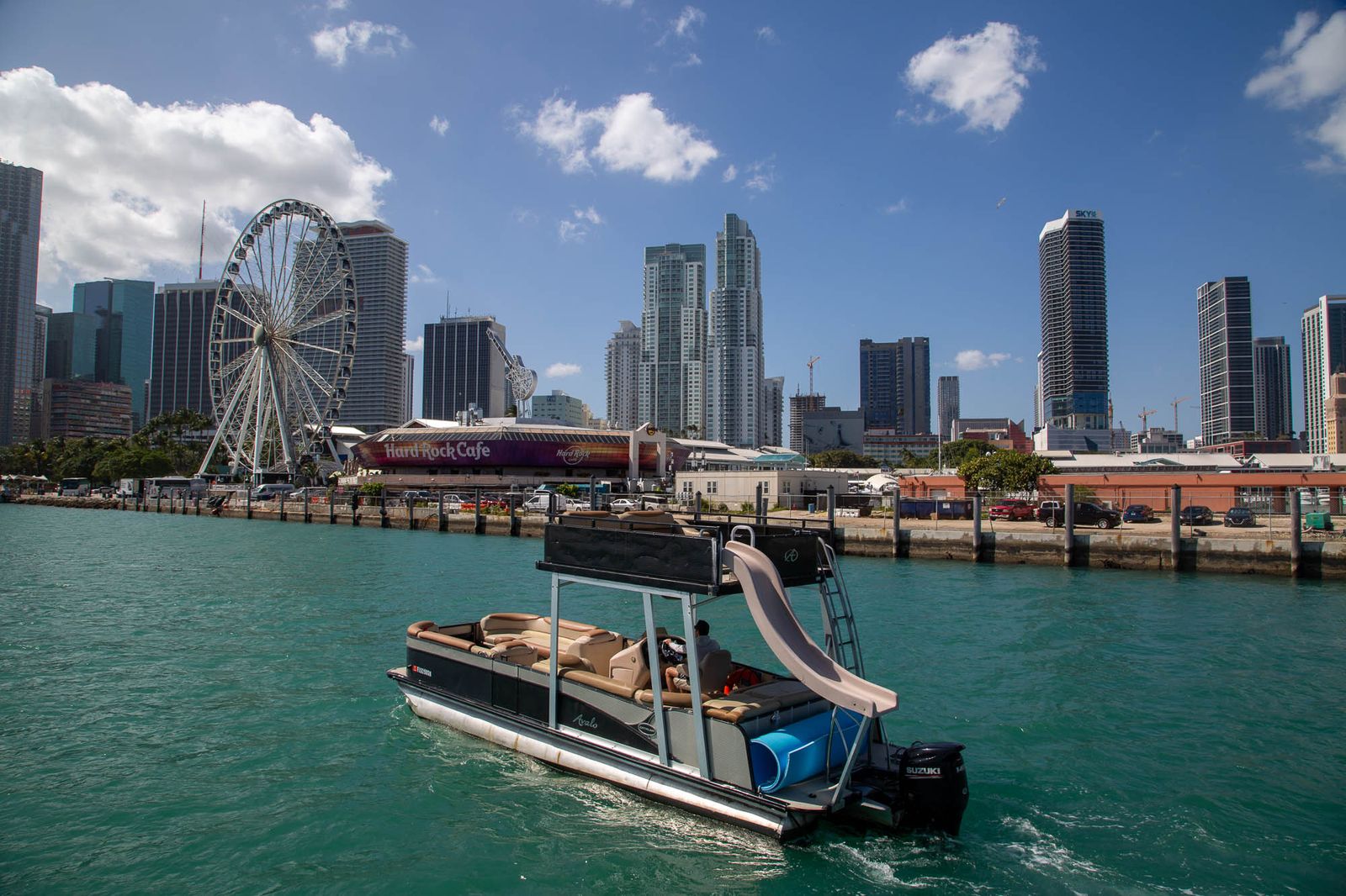 Double-deck tritoon cruising past the Miami skyline and Ferris wheel